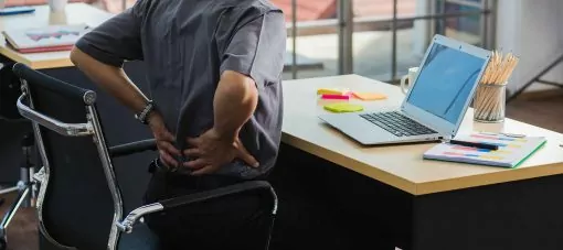 Un homme travaillant avec un ordinateur portable a un problème de mal de dos. Vieil homme ressentant de la douleur après être resté assis à un bureau pendant longtemps, concept de syndrome du cabinet de soins de santé et de médecine